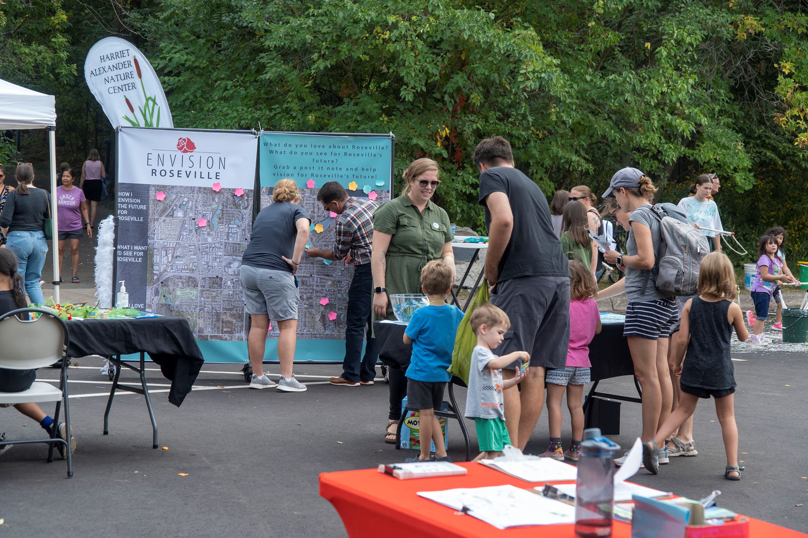 Community-members talk at the Envision Roseville booth at Wild Rice Festival.